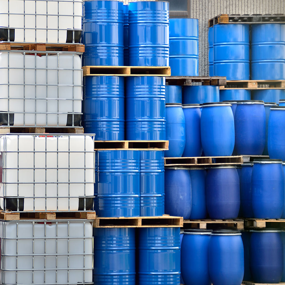 IBC Totes, 55 gallon drums, and pallets stacked in a warehouse